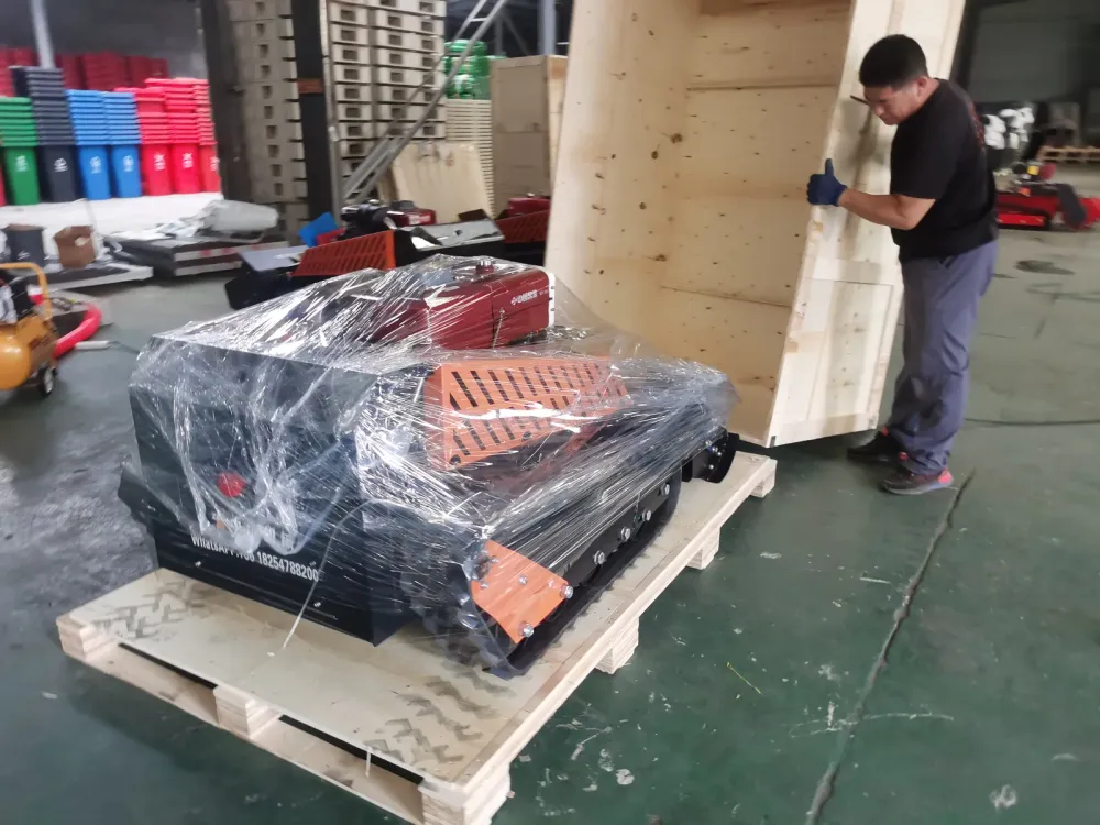 Mower wrapped in stretch film on its pallet while a worker positions the first plywood crate wall