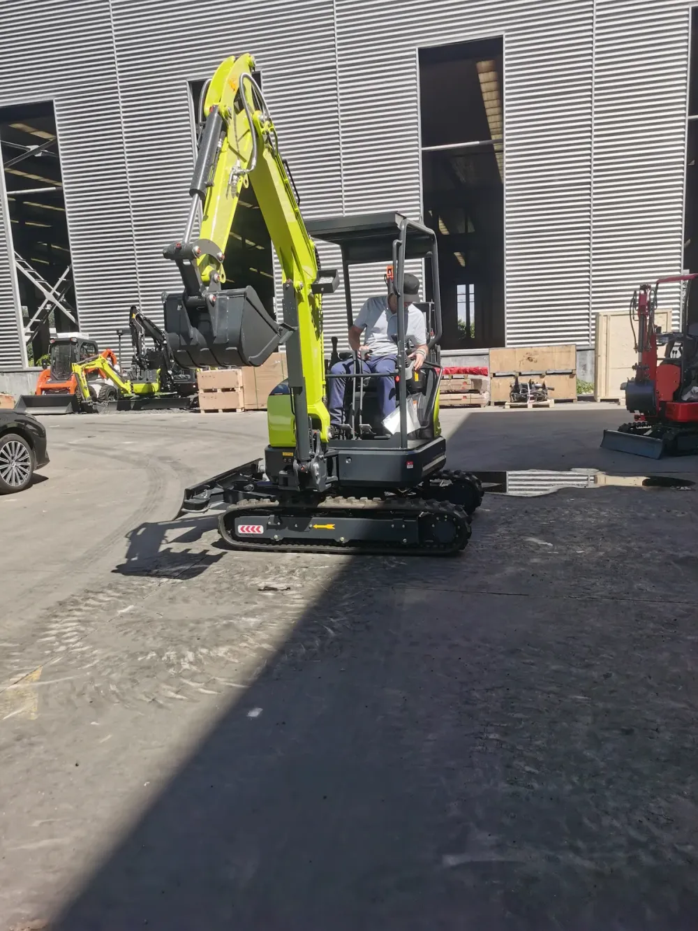 Visiting buyer operating a canopy mini excavator, working the boom and bucket in the test area
